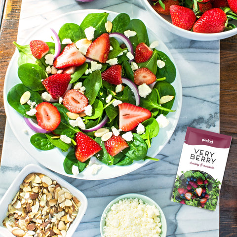 Very Berry salad dressing single serve packet next to strawberry salad with feta. 